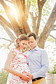 Pregnant Caucasian couple hugging outdoors