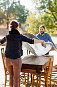 Caucasian couple spreading tablecloth on outdoor table