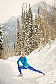 Caucasian woman stretching in snow