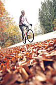 Young woman riding with her bike on a street, Fuessen, Bavaria, Germany