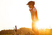 girl putting on her bicyle helmet on a meadow, Fuessen, Bavaria, Germany
