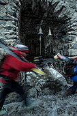 Zwei junge Skifahrer laufen an kleinen Glocken einer Ruine vorbei, Gudauri, Mzcheta-Mtianeti, Georgien