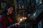 Junge Frau entzündet Kerzen in einer kleinen Kirche, Gudauri, Mzcheta-Mtianeti, Georgien