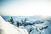 Zwei junge Skifahrer steigen durch den Tiefschnee auf den Gipfel eines Berges, Gudauri, Mzcheta-Mtianeti, Georgien