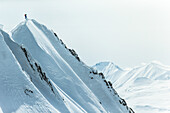 Junger Skifahrer steigt durch den Tiefschnee auf den Gipfel eines Berges, Gudauri, Mzcheta-Mtianeti, Georgien