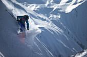 Young male skier riding apart the slopes through the deep powder snow, Gudauri, Mtskheta-Mtianeti, Georgia