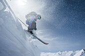 Young female skier jumping down a snowdrift in the mountains, Gudauri, Mtskheta-Mtianeti, Georgia
