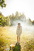 Kind nach der morgendlichen Dusche auf einer Wiese im Sonnenlicht, Halland, Sweden