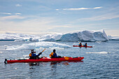 Passagiere von Expeditions Kreuzfahrtschiff MV Sea Spirit (Poseidon Expeditions) paddeln im Seekajak entlang Eisschollen und Eisbergen, Cierva Cove, Grahamland, Antarktische Halbinsel, Antarktis