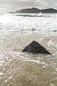 pointed boulder in sand, surf, beach, ocean, high format, North Island, New Zealand