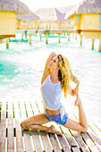 Frau macht Yoga vor Überwasserbungalows, Le Taha'a Resort, Tahiti, Französisch-Polynesien, Südpazifik, Pazifik