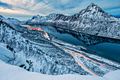 Die schneebedeckten Gipfel über dem gefrorenen Meer umrahmt von den blauen Lichter der Dämmerung, Gryllefjorden, Senja, Troms County, Arktis, Norwegen, Skandinavien, Europa