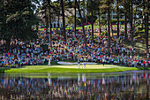 Spectators fill the hill behind the 9th green of the Par 3 course as players finish their round at Augusta National Golf Club, Augusta, Georgia, United States of America, North America