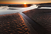 Sunset over beach streams and sand pools at Llanddwyn beach at very low tide, West Anglesey, Wales, United Kingdom, Europe