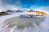 Lake Scermendone during the vernal thaw reflecting Mount Disgrazia at sunset Valtellina, Sondrio, Lombardy, Italy. Europe.