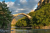 The old stone bridge across the Aoos river at Konitsa with Mount Tymfi in the background, Epirus, Northern Greece.