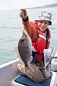 A young boy who has just caught a fish.