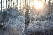 Junger Läufer streht in einen mit Frost bedeckten Wald, Allgäu, Bayern, Deutschland