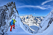 Two persons backcountry skiing standing in notch and looking towards Dachstein group, Stuhlloch, Bischofsmuetze, Gosau group, Dachstein, UNESCO World Heritage Site Salzkammergut-Dachstein, Salzburg, Austria