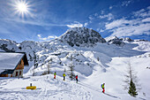 Four persons backcountry skiing descending from hut Laufener Huette, Fritzerkogel in background, hut Laufener Huette, Tennengebirge range, Salzburg, Austria