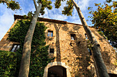 Gala Dali Castle Museum facade amidst tall trees, medieval home of Salvador Dali, Pubol, Baix Emporda, Girona, Catalonia, Spain, Europe