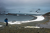 Tourist photographing from an overlook over Half Moon Island, South Shetland Islands, Antarctica, Polar Regions