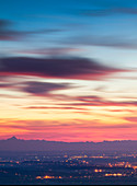 Pavese hills, Lombardy, Italy, The lights of Padana plain are under the sunset, with the Alp's profiles