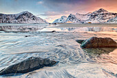 Pink sky on the surreal Skagsanden beach surrounded by snow covered mountains, Lofoten Islands Northern Norway Europe
