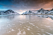 Pink sky on the surreal Skagsanden beach surrounded by snow covered mountains, Lofoten Islands Northern Norway Europe