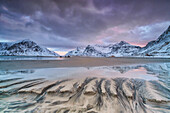 Waves on the surreal Skagsanden beach surrounded by snow covered mountains, Lofoten Islands Norway, Europe