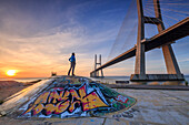A tourist admires the majestic Vasco da Gama Bridge over the River Tagus Parque das Na+º+Áes Lisbon Portugal Europe