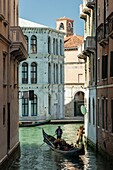 People enjoying a gondola ride on a canal in Cannareggio, Venice, Italy.
