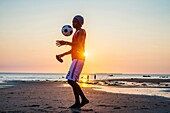 A man plays with a ball on the local beach near Stone Town, Zanzibar, Tanzania.