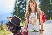 Happy young female child having fun with her dog while going walkies in Bavarian mountains, Brauneck, Germany