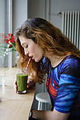 Side view of young woman drinking juice at cafe
