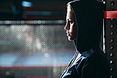 Close-up side view of woman wearing hooded shirt standing at gym