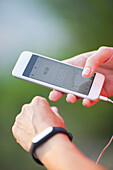 Cropped image of woman using pedometer and mobile phone