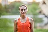 Portrait of young woman listening to headphones at park