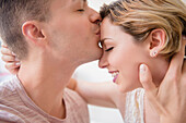 Caucasian man kissing girlfriend on forehead