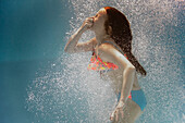 Caucasian girl swimming underwater holding nose