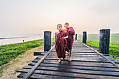 Amarapura, Mandalay region, Myanmar, Monks walking on the U Bein bridge at sunrise