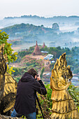 Mrauk-U, Rakhine state, Myanmar, Man taking pictures of Mrauk-U in a foggy sunrise from the Shwetaung pagoda