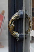 France, Paris, closeup on a gilt bronze handle of a shop representing two clasped hands