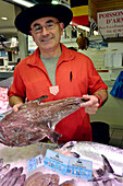 France, Brittany, Finistere, Concarneau, inside of the covered market, particularly well-assorted fishery. Fishmonger with an anglerfish