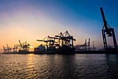 Sonnenaufgang an einem Wintertag im Hamburger Hafen am Containerterminal Burchardkai von der Elbfähre aus gesehen, Hamburg, Deutschland