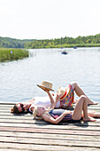 Mother and daughter lying on swimming platform, reading, sunbathing,  straw hat, swimming in a lake, beach, playing in the water, lake Granzower Möschen, holiday, summer, Mecklenburg lakes, Mecklenburg lake district, MR, Granzow, Mecklenburg-West Pomerani