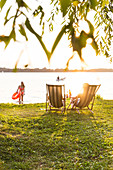 Beach at lake Plauer See, camping ground, willow, sunset, beach chair, swimming, summer, Mecklenburg lakes, Mecklenburg lake district, Zislow, Mecklenburg-West Pomerania, Germany, Europe