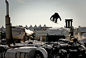 A Snowboarder Taking Off From A Jump In A Snowcovered Junkyard
