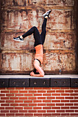 Woman Doing Exercise On Top Of Brick Wall