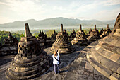 Woman Taking Pictures Of Stupas On Borobudur Temple In Indonesia
